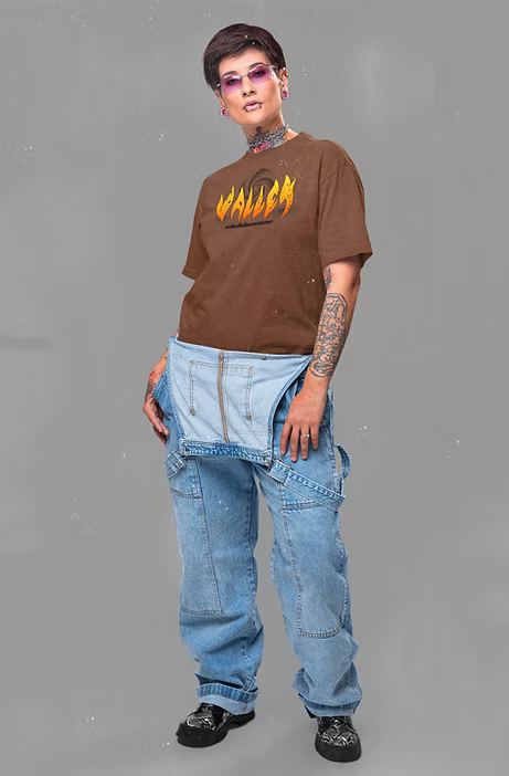 Person wearing a brown t-shirt with a graphic design and blue jeans on a gray background