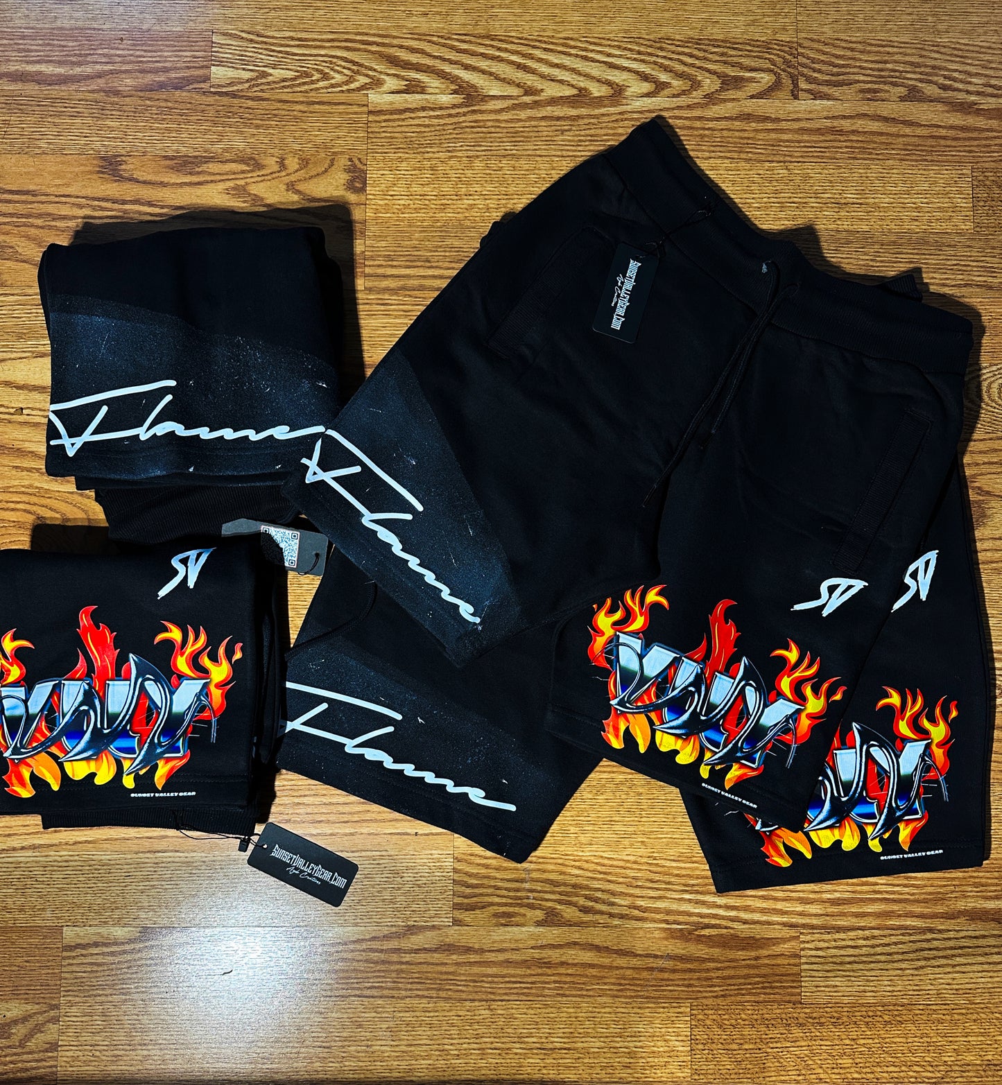 Black shorts with flame design By Sunset Valley Gear and branding on a white and black abstract background