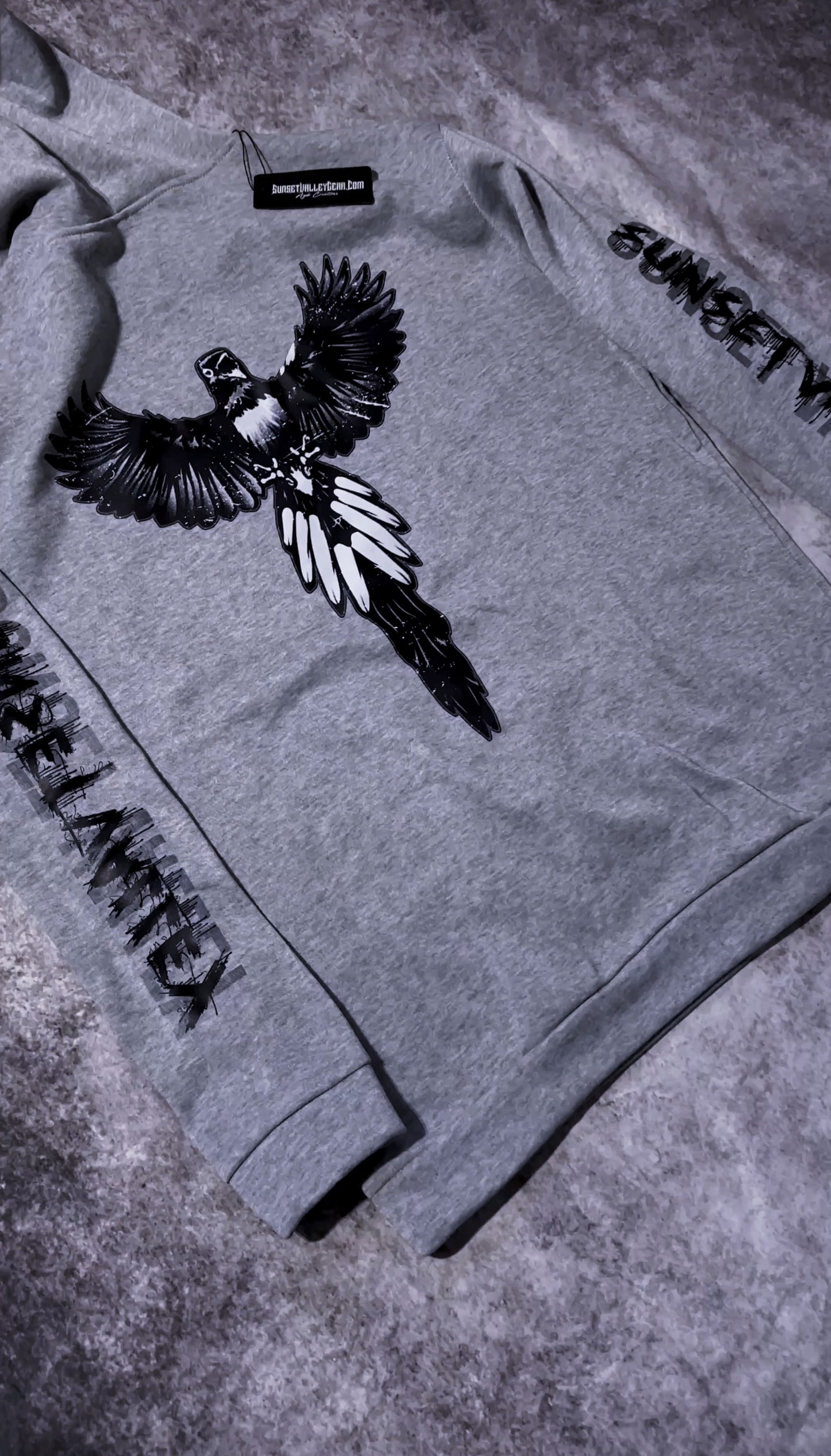 Gray sweatshirt with a bird design and text on a textured surface