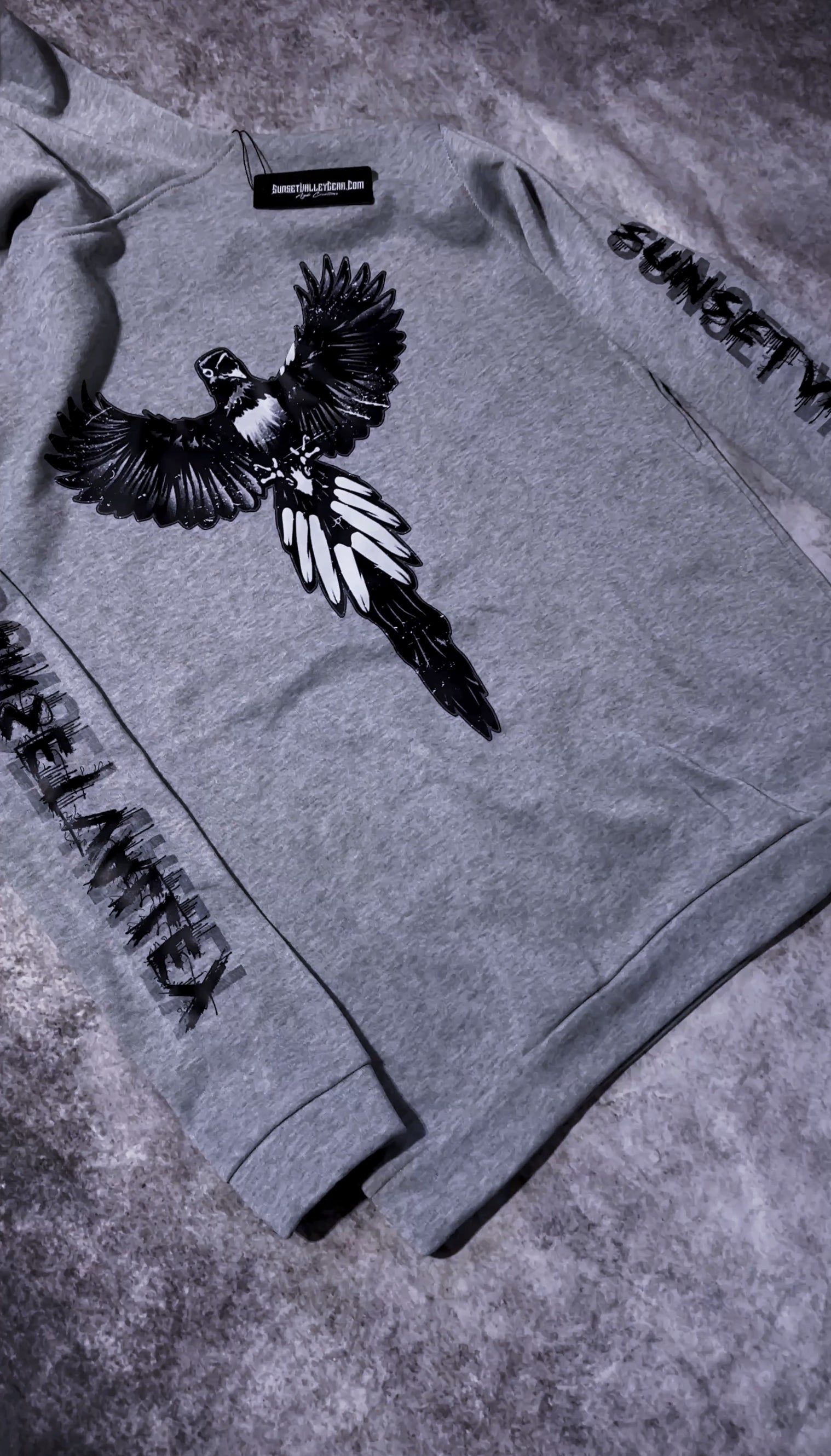 Gray sweatshirt with a bird design and text on a textured surface